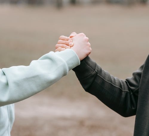 The arms of two individuals in a warm handshake